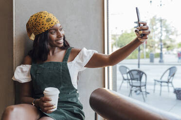 Woman taking selfie through smart phone at cafe - JRVF00508