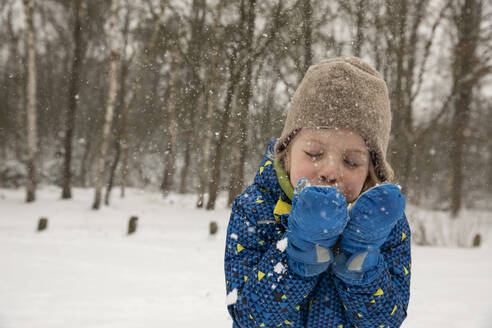 Boy blowing snow from hands during winter - FVDF00001