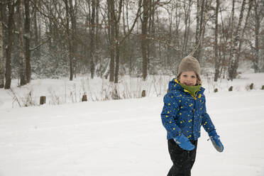 Lächelnder Junge in warmer Kleidung, der im Winter im Schnee steht - FVDF00002