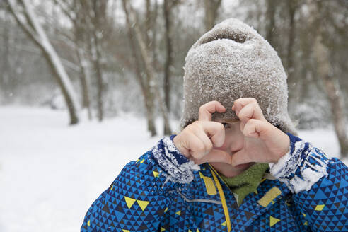 Junge in warmer Kleidung macht Herzform im Winter - FVDF00005