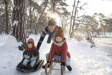 Vater schlittelt mit seinen Söhnen im Winter durch den Schnee - FVDF00030