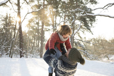 Playful father picking up son during winter - FVDF00031