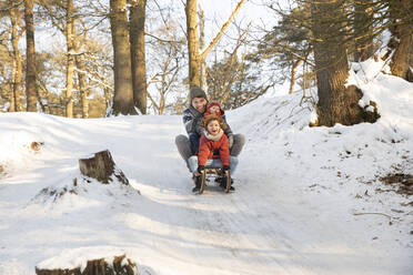 Familie schlittelt im Winter durch den Schnee - FVDF00048