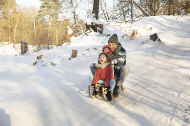 Verspielter Junge schlittert mit Vater und Bruder im Winter durch den Schnee - FVDF00050