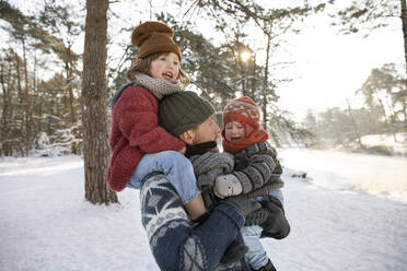 Father carrying boy on shoulder while looking at crying son during winter - FVDF00061