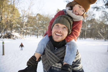 Father looking up while carrying son on shoulder during winter - FVDF00064