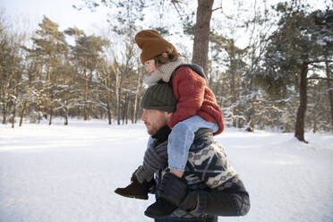 Father holding son sitting on shoulder during winter - FVDF00065