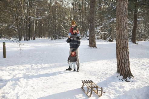 Vater mit Söhnen im Schnee stehend im Winter - FVDF00066