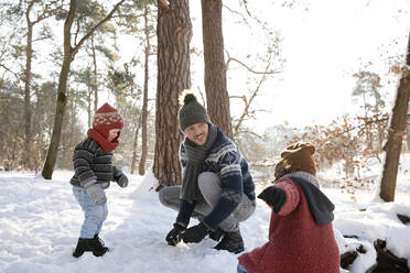 Father playing with sons on snow during winter - FVDF00080