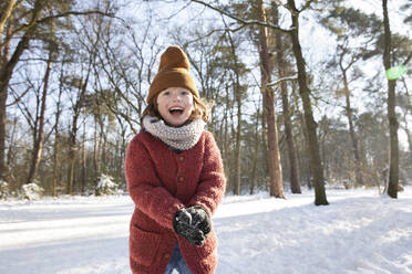 Neugieriger Junge in warmer Kleidung, der im Winter mit Schnee spielt - FVDF00081