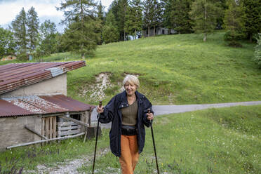 Frau geht auf Gras und hält einen Wanderstock in der Provinz Brescia, Lombardei, Italien - MAMF01752