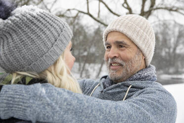 Mann mit Strickmütze sieht Frau im Winter an - FVDF00087