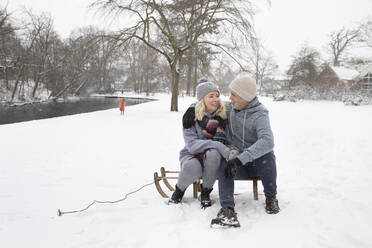 Ehepaar sitzt im Winter auf einem Schlitten - FVDF00091