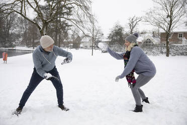 Älteres Paar bei einer Schneeballschlacht im Winter - FVDF00103