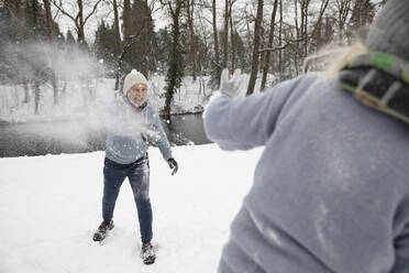 Verspielter Mann, der im Winter Schnee auf eine Frau wirft - FVDF00105