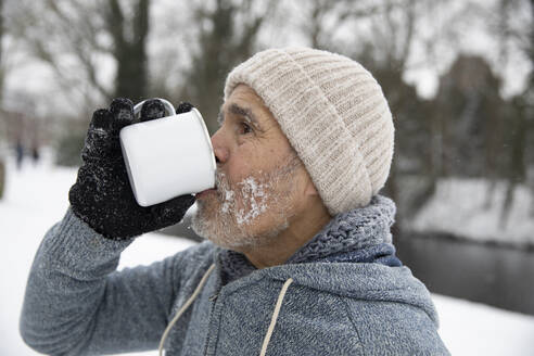 Mann trinkt im Winter Tee in einem Becher - FVDF00115
