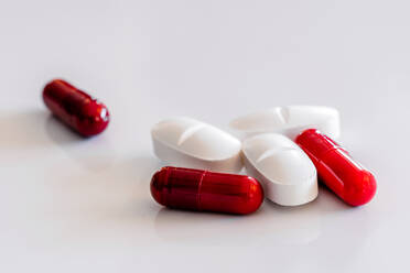 Assorted colorful and white pills and capsules placed on white table - ADSF23455