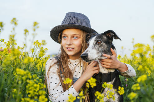 Girl wearing sun hat with dog looking away - JCMF01961