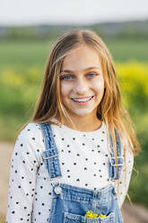Smiling blond girl standing at agricultural field - JCMF01969
