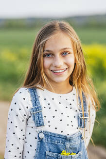 Lächelndes blondes Mädchen auf einem landwirtschaftlichen Feld - JCMF01969