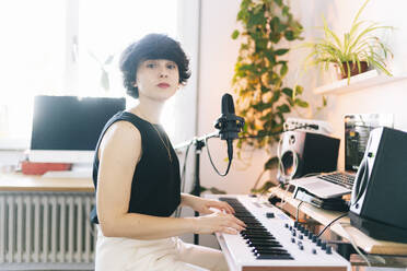 Female composer using electric piano in studio - DGOF02164