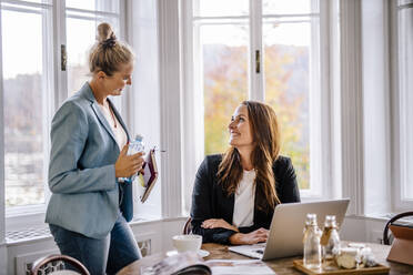 Lächelnde Geschäftsfrauen im Gespräch mit einer Kollegin im Büro - DAWF01982