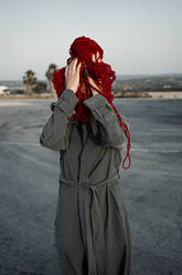 Frau, die ihr Gesicht mit einem Faden bedeckt, steht auf der Straße - RCPF00994