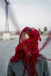 Frau bedeckt Gesicht mit rotem Faden auf der Straße - RCPF00997