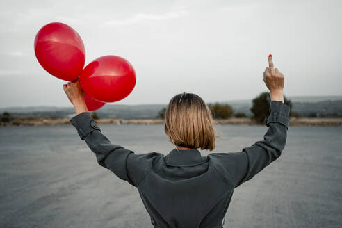 Blonde Frau hält Ballon und zeigt obszöne Geste auf der Straße - RCPF01005