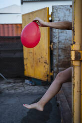 Frau hält roten Luftballon im Freien - RCPF01015