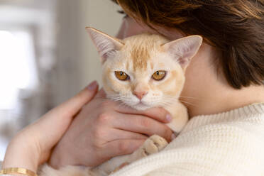 Junge Frau trägt Katze auf Schulter zu Hause - EYAF01589