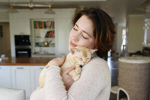 Beautiful woman embracing cat at home - EYAF01594