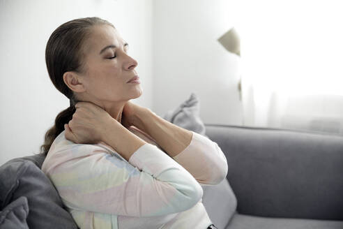 Tired woman siting with eyes closed on sofa - FLLF00605