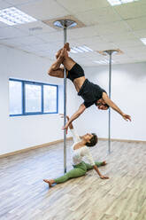 Mid adult male and female dancers practicing on rod in studio - DLTSF01812