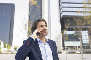 Male entrepreneur talking on mobile phone in city - JCCMF02028