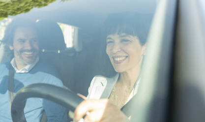 Smiling businesswoman driving car by man - JCCMF02087