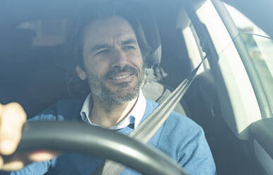 Mature male entrepreneur smiling while driving car - JCCMF02093