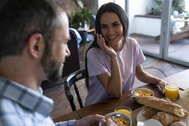 Woman looking at man while having breakfast on dining table at home - OIPF00566