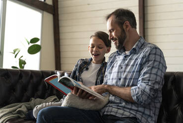 Vater und Sohn lesen ein Buch, während sie zu Hause sitzen - OIPF00573