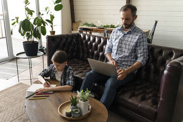 Vater benutzt Laptop, während Sohn zu Hause zeichnet - OIPF00577