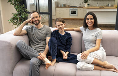 Happy family sitting on sofa in living room at home - OIPF00617