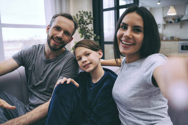 Familie, die ein Selfie macht, während sie im Wohnzimmer zu Hause sitzt - OIPF00618
