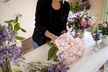 Frau macht Blumenarrangement auf einem Tisch in einer Werkstatt - MPPF01715