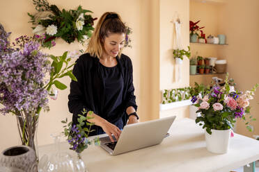 Floristin arbeitet in der Werkstatt am Laptop - MPPF01720