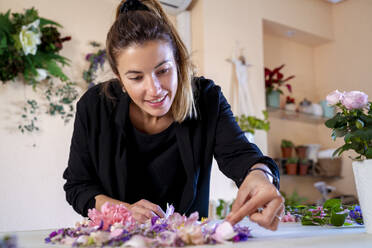 Woman arranging flowers at workshop - MPPF01730
