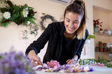 Glückliche Floristin bei der Herstellung von Blumenschmuck in einem Workshop - MPPF01731