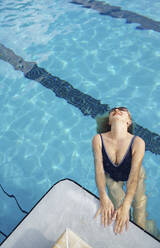 Reife Frau trägt ein Stück Badeanzug lächelnd im Schwimmbad - AZF00304