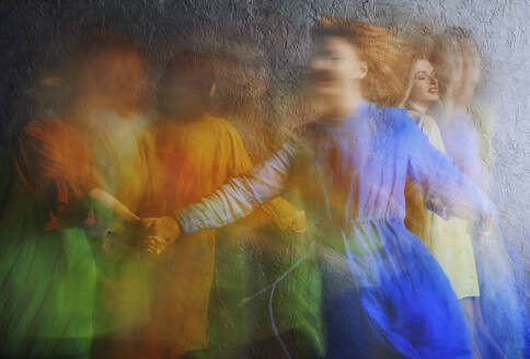 Female friends in colorful dress dancing together - AZF00310