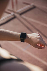 Sportswoman checking smart watch during sunny day - RSGF00647