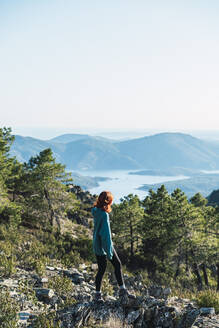 Junge Frau betrachtet die Aussicht, während sie auf einem Berg steht - RSGF00652
